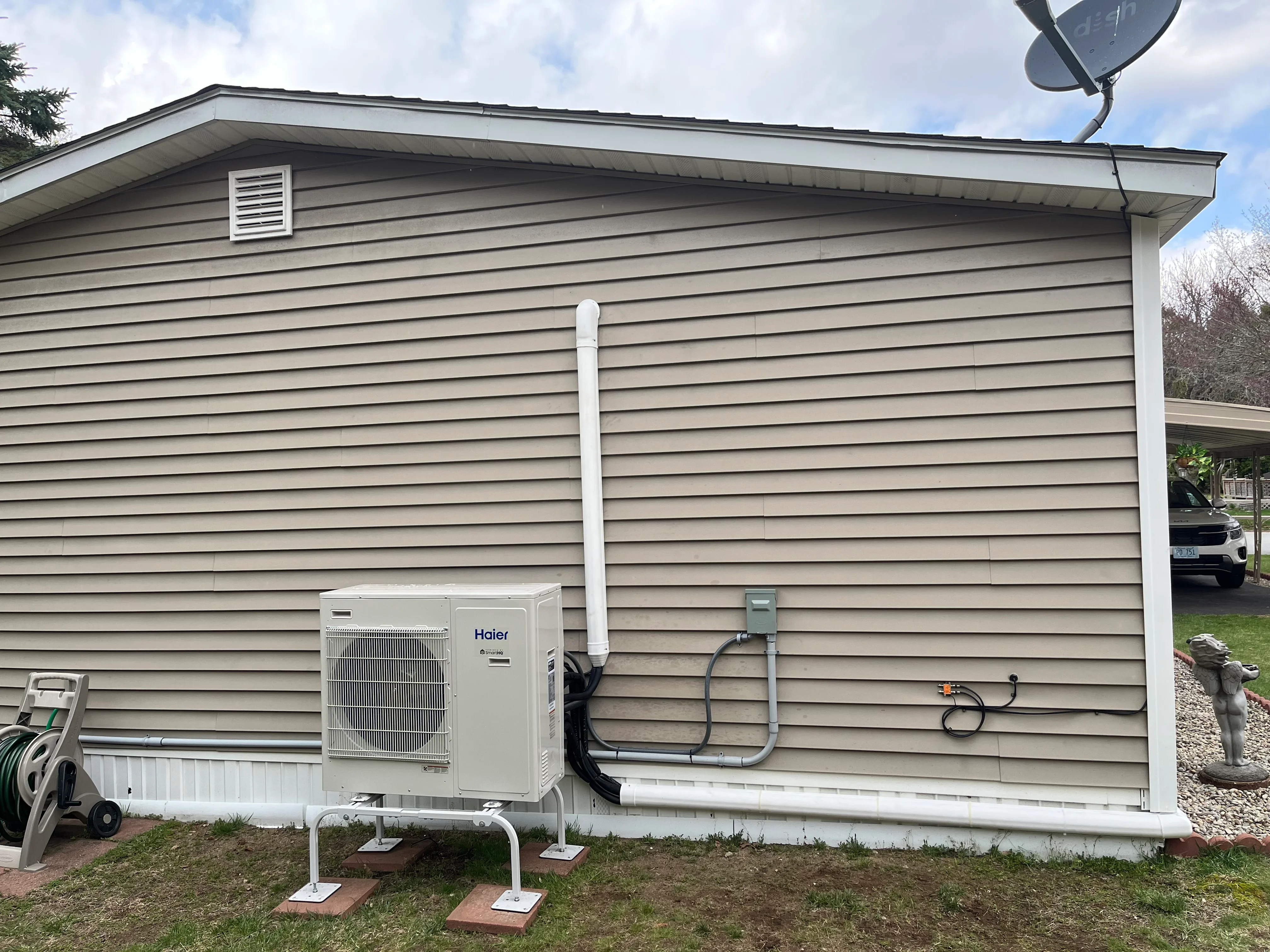 Haier ductless mini-split condenser unit installed on concrete pad with white refrigerant line routing