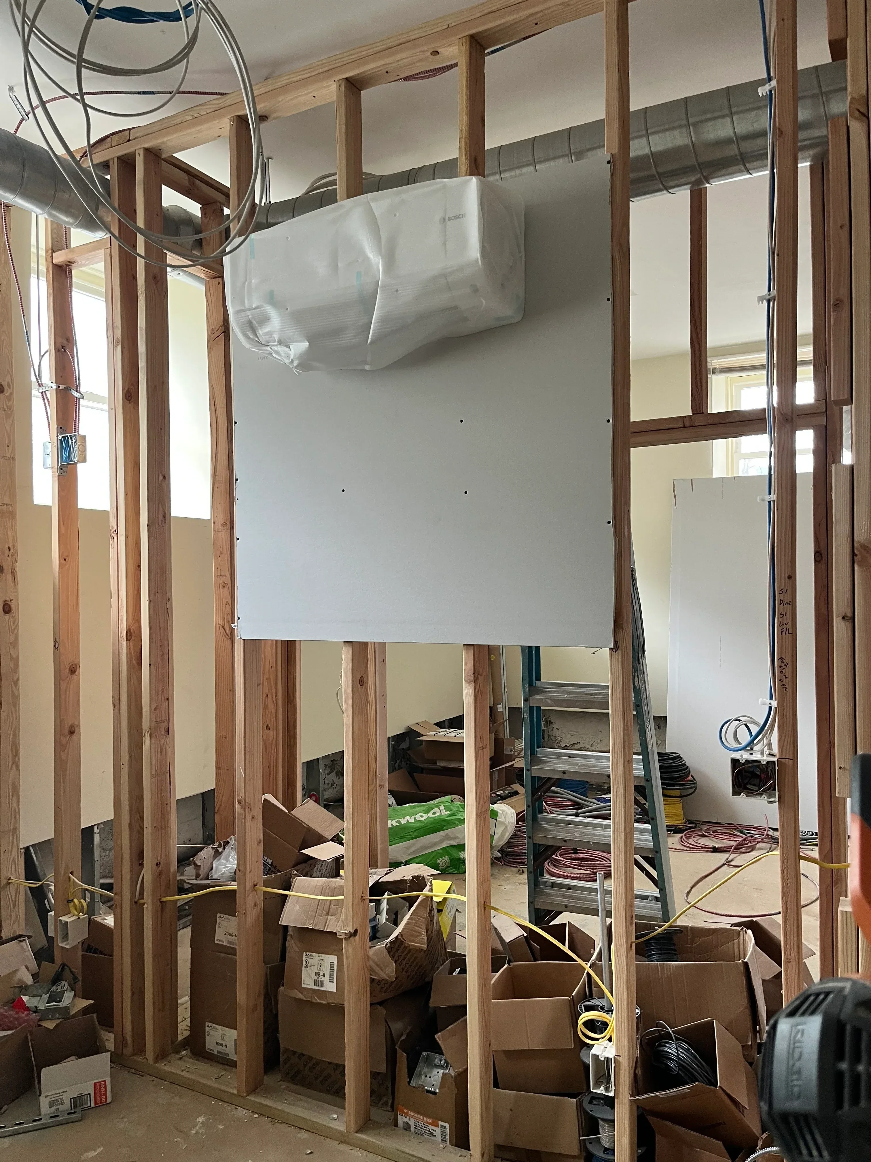 HVAC ductwork installation with air handler unit and electrical wiring in framed ceiling cavity