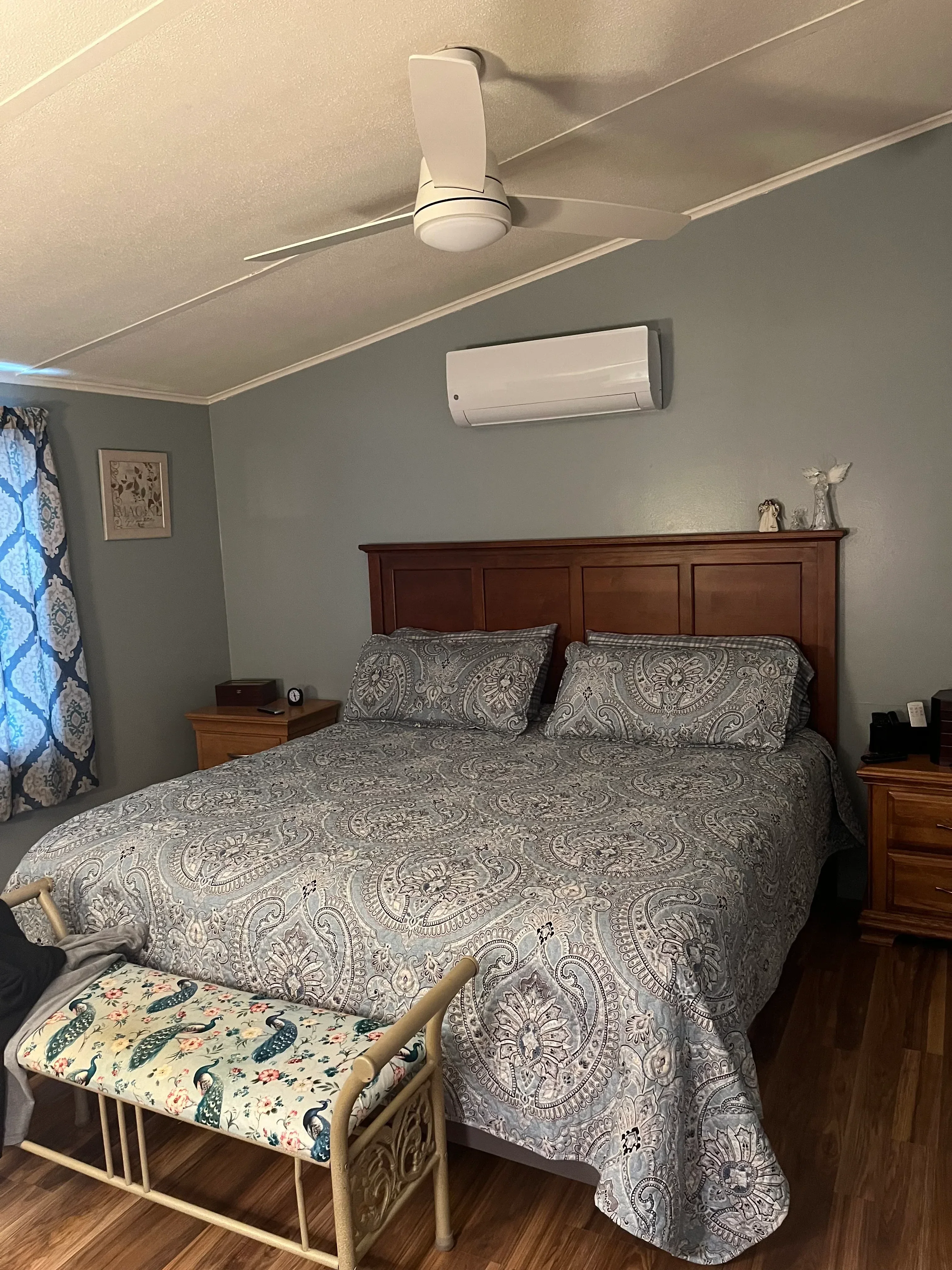 Wall-mounted HVAC unit and thermostat installed in bedroom with hardwood floors