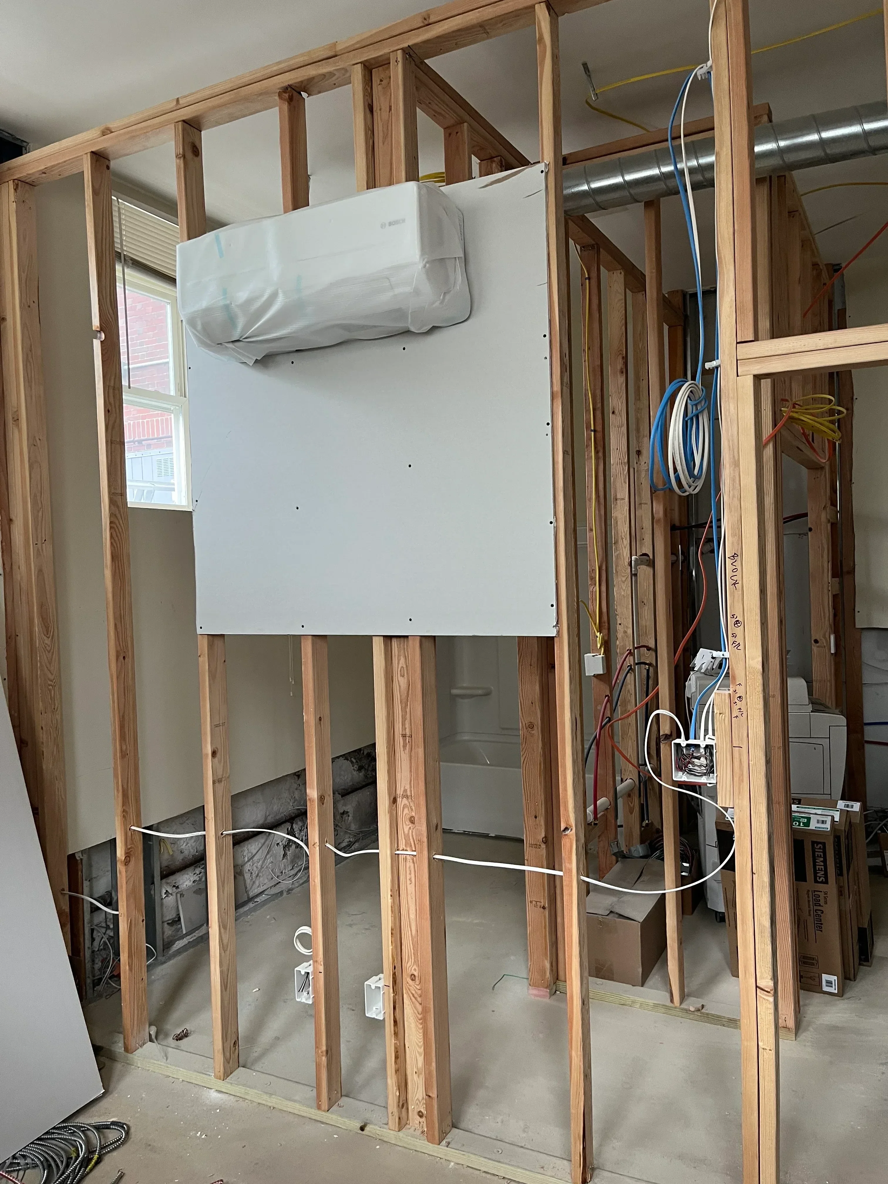 In-wall HVAC installation with framed cavity, ductwork, wiring, and access panel